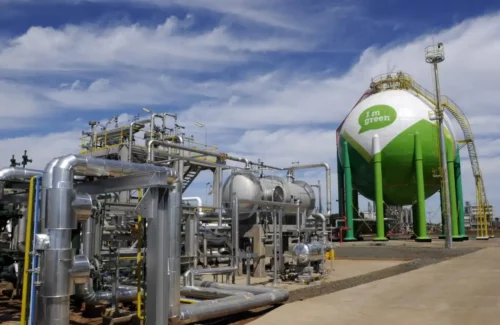 Instalações industriais da Braskem com tanques, tubulações e estrutura petroquímica sob céu parcialmente nublado.
