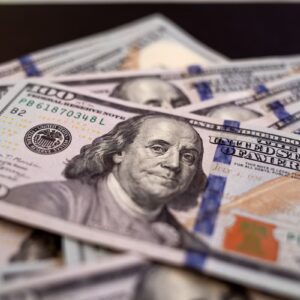 Notas de dólar americano de 100 dólares espalhadas, representando câmbio, mercado financeiro e valorização da moeda.