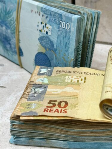 Cédulas de real representando a devolução do auxílio emergencial cobrada pelo governo federal