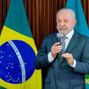 Presidente Lula discursa diante da bandeira do Brasil durante evento oficial em Brasília.