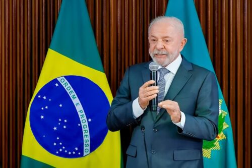 Presidente Lula discursa diante da bandeira do Brasil durante evento oficial em Brasília.