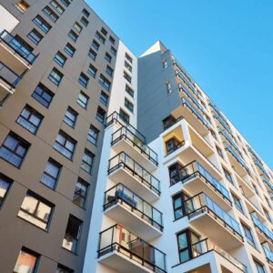 Prédios residenciais com apartamentos e varandas sob céu azul, imagem usada para ilustrar o mercado imobiliário.