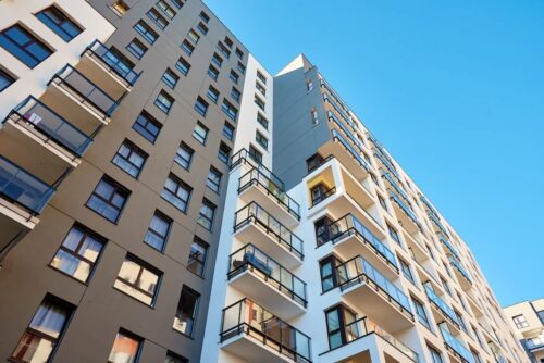 Prédios residenciais com apartamentos e varandas sob céu azul, imagem usada para ilustrar o mercado imobiliário.