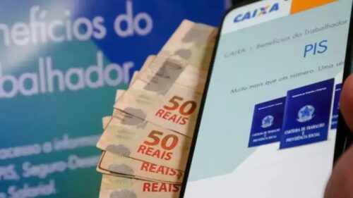 Celular exibe consulta ao PIS ao lado de notas de real, ilustrando pagamento do abono salarial.