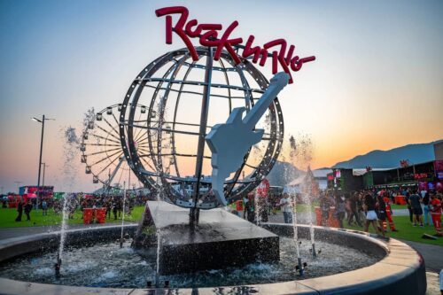 Público circula pelo espaço do Rock in Rio ao redor da icônica guitarra gigante durante o pôr do sol no festival.