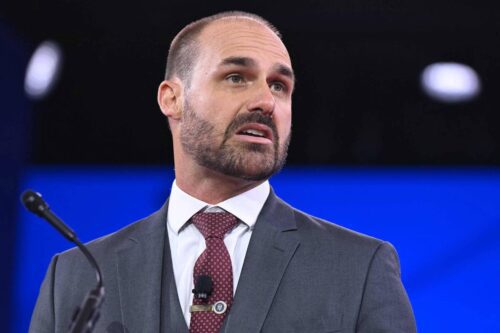 Eduardo Bolsonaro fala em evento, usando terno e gravata, durante participação em conferência nos Estados Unidos.