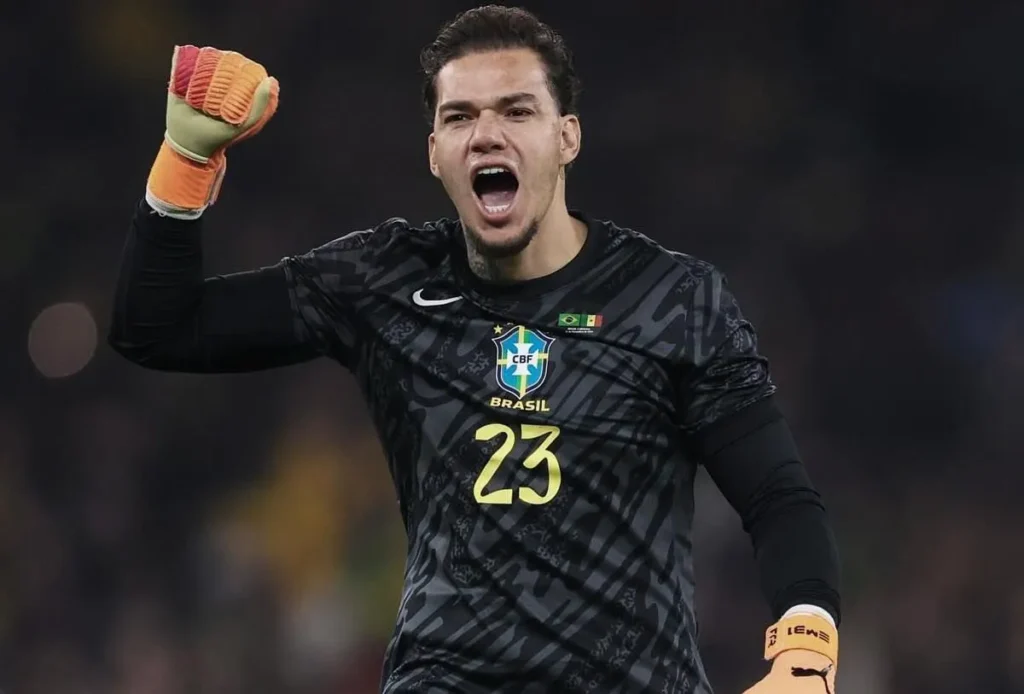 Ederson comemora durante partida com a camisa da Seleção Brasileira e uniforme de goleiro preto.