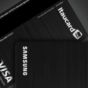 Dois cartões de crédito pretos com textura de metal escovado, sobrepostos em um fundo cinza-escuro. O cartão em primeiro plano mostra a parte frontal, destacando um chip eletrônico prateado no canto inferior direito e a palavra "SAMSUNG" escrita verticalmente em letras brancas na lateral esquerda. O cartão ao fundo mostra o verso, exibindo a tarja magnética preta no topo, o logotipo prateado "VISA Platinum" no canto inferior esquerdo, e o logotipo "itaucard" com o ícone do Banco Itaú no canto superior direito. Números de telefone de atendimento em letras pequenas também são visíveis no verso do cartão.