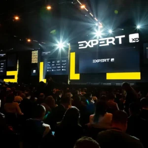 Palco da Expert XP 2026 com palestrantes e plateia acompanhando apresentações sobre investimentos e economia.