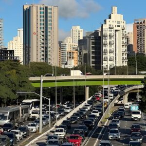 Trânsito intenso em avenida de São Paulo durante o feriado estadual de 9 de julho, com carros e prédios ao fundo.
