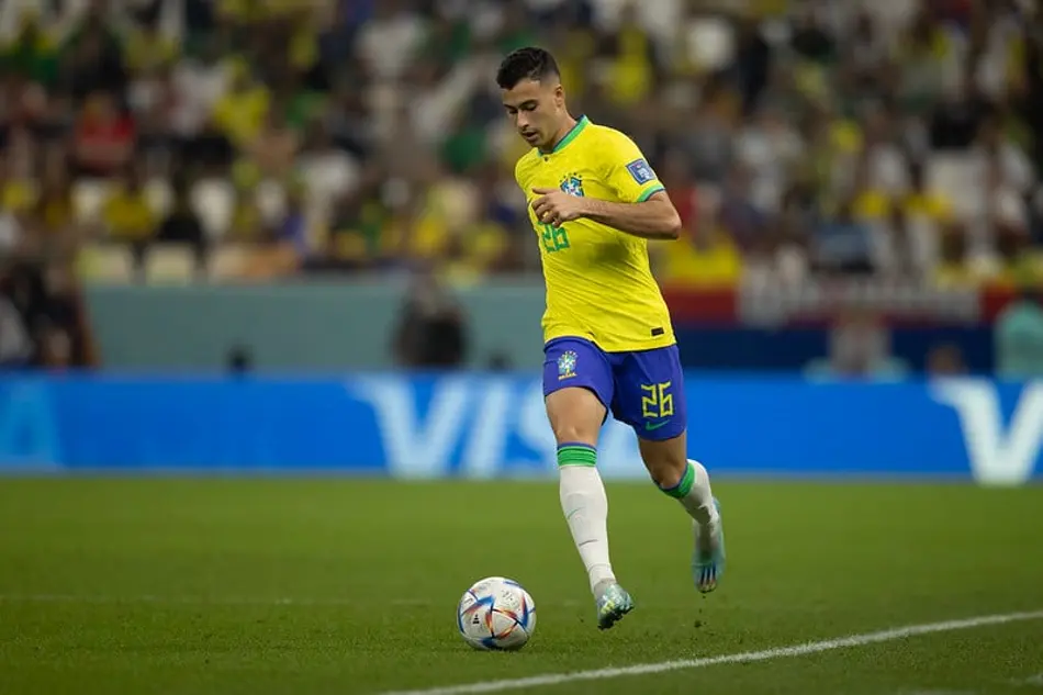 Gabriel Martinelli conduz a bola com a camisa da Seleção Brasileira durante partida em estádio de futebol.