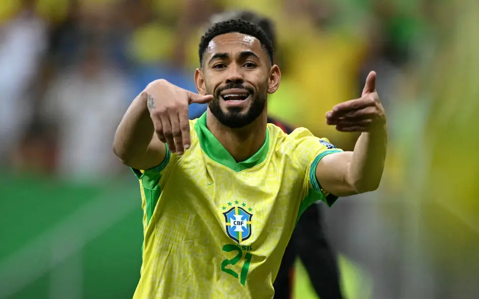 Matheus Cunha comemora durante partida com a camisa da Seleção Brasileira em estádio de futebol.