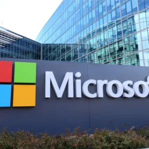 Logotipo da Microsoft em frente ao prédio da empresa, destacando investimento em inteligência artificial.