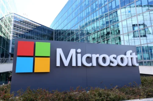 Logotipo da Microsoft em frente ao prédio da empresa, destacando investimento em inteligência artificial.