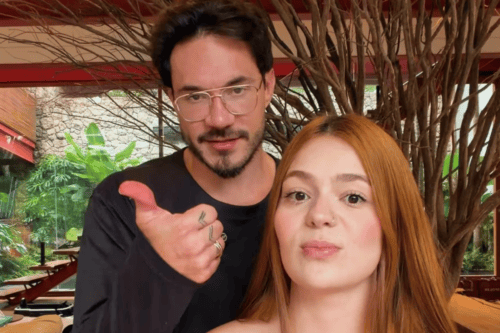 Uma foto em plano fechado da influenciadora digital Viih Tube e de seu parceiro Eliezer. À direita, Viih Tube aparece em primeiro plano, encarando a câmera com uma expressão séria; ela tem longos cabelos ruivos e lisos, pele clara e um pequeno piercing no nariz. Logo atrás dela e ligeiramente à esquerda, Eliezer olha para a câmera com um leve sorriso.