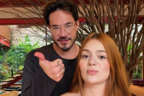 Uma foto em plano fechado da influenciadora digital Viih Tube e de seu parceiro Eliezer. À direita, Viih Tube aparece em primeiro plano, encarando a câmera com uma expressão séria; ela tem longos cabelos ruivos e lisos, pele clara e um pequeno piercing no nariz. Logo atrás dela e ligeiramente à esquerda, Eliezer olha para a câmera com um leve sorriso.
